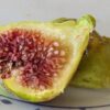 une figue blanche bien mûre de ficus carica Blanche d'Argenteuil coupée en deux sur une assiette