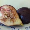 une figue coupée en deux Bursa Brown, un côté chair, un côté peau, sur une assiette