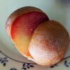 fruit d'un hybride interspecifique dapple supreme prune-abricot, mûr, posé sur une assiette, coupé en deux, un côté chair, un côté peau