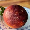 une orange sanguine à chair rouge foncé posée sur une assiette