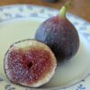 une belle figue mûre d'un ficus carica black jack coupée en deux sur une assiette, un côté chair, un côté peau