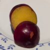 Une prune hybride flavor grenade bien mûr coupée en deux