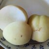 Fruit de Prunus persica Icepeach donne des fruits à la peau et chair blanches, ici coupé en deux, un côté chair, un côté peau